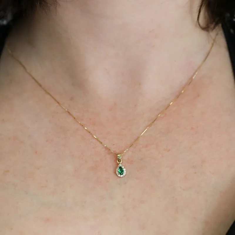 A drop-shaped halo pendant with a green zircon stone on a 14K gold Venetian chain.